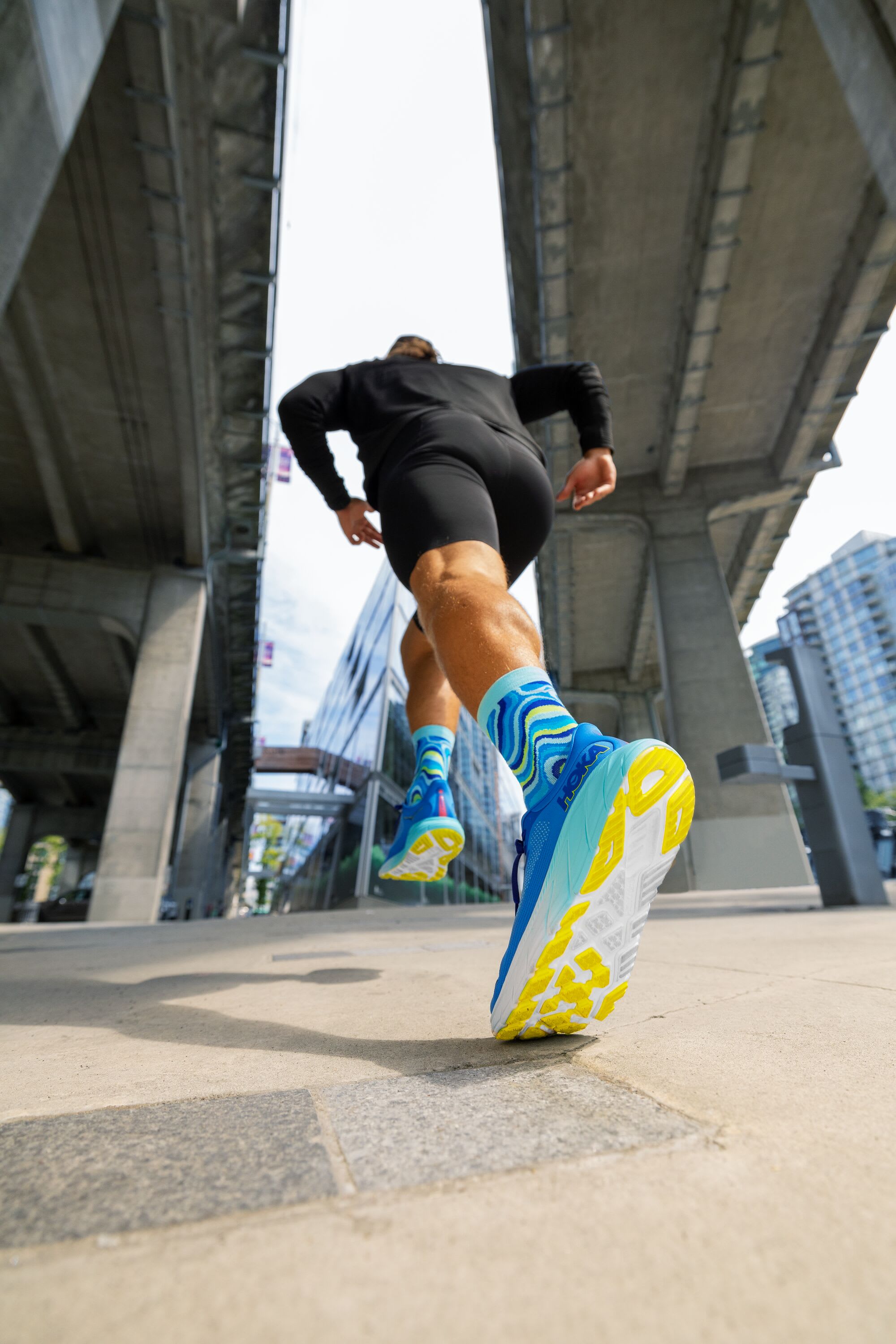 A rear up close view of a runners HOKA Shoe emphasizing the outer sole and socks