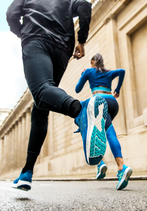 A rear view of a Male and Female runner emphasizing their footwear and leggings in the forefront